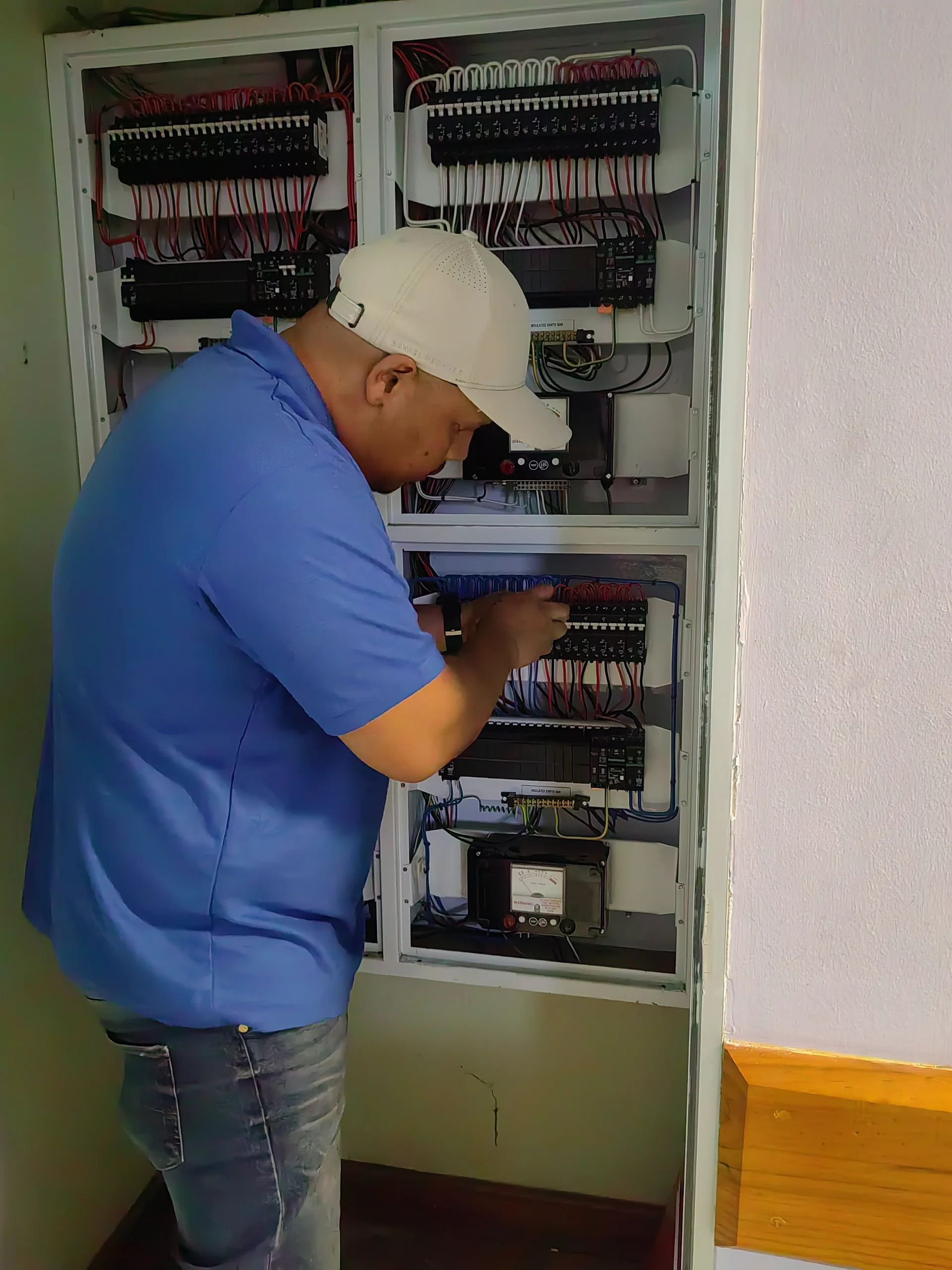 Close-up of an electrician connecting wires inside an electrical panel